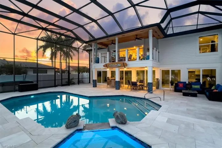 Pool at dusk with a hot tub, ceiling fan, a patio, and a lanai