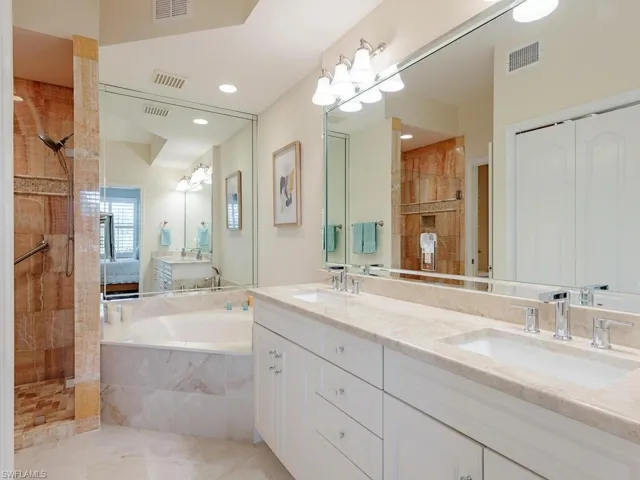 Bathroom featuring visible vents, a sink, and a tile shower