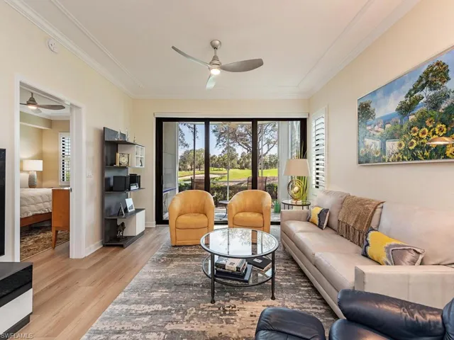Living room featuring baseboards, a ceiling fan, light wood-style flooring, and crown molding