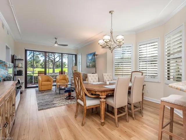 Dining room with light wood-style floors, ornamental molding, baseboards, and ceiling fan with notable chandelier