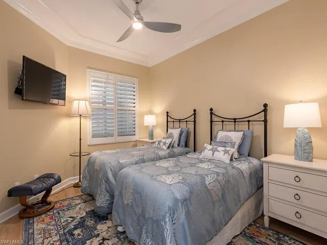 Bedroom with a ceiling fan, baseboards, crown molding, and wood finished floors