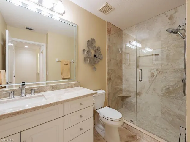 Bathroom with visible vents, a shower stall, toilet, and vanity