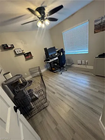 Interior room featuring wood-finish flooring, a contemporary ceiling fan with integrated lighting, and a window with horizontal blinds
