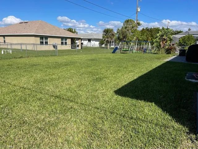 Fenced backyard featuring a playground