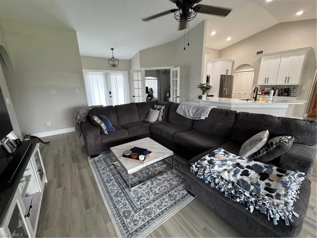 Spacious living area featuring vaulted ceilings, wood-finish flooring, and recessed lighting