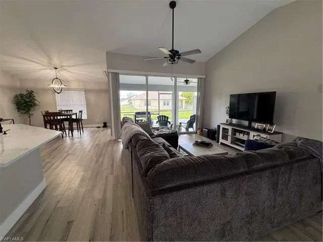 Spacious living area featuring vaulted ceilings, wood-finish flooring, and a contemporary ceiling fan