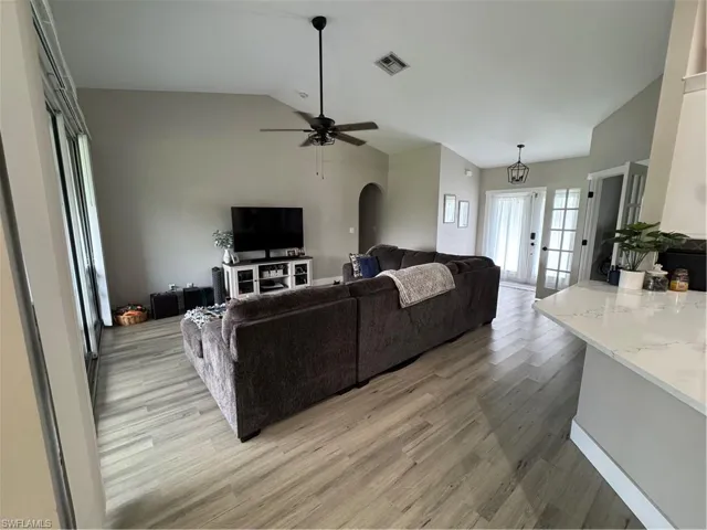 Spacious living area featuring wood-finish flooring, vaulted ceilings, and a ceiling fan