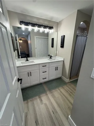 Dual vanity with white cabinetry, matte black hardware, and light-toned countertop