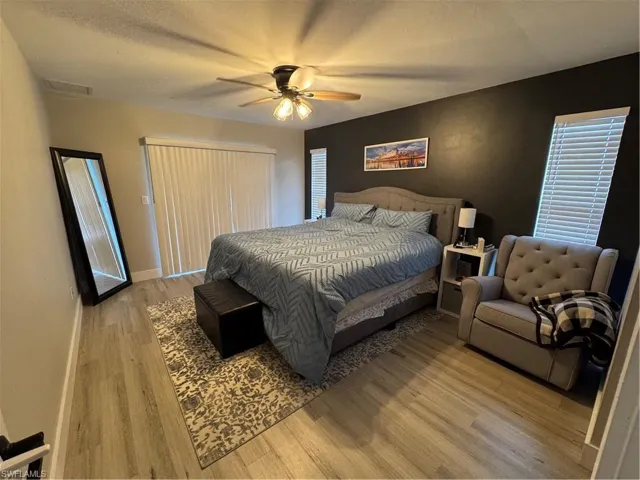 Room featuring wood-finish flooring, a ceiling fan with integrated lighting, and a dark accent wall