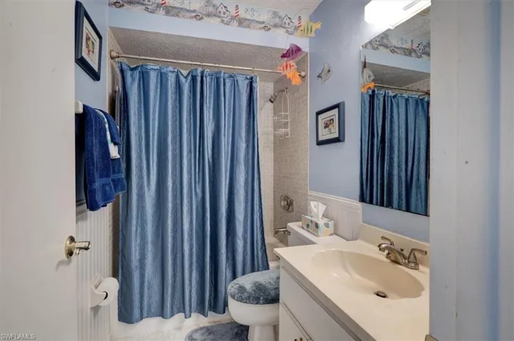Full bathroom with shower / tub combo with curtain, vanity, a textured ceiling, and toilet