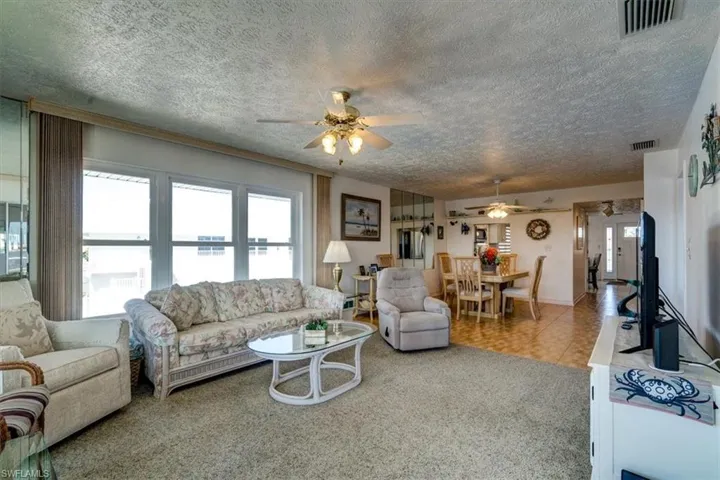 Carpeted living room featuring ceiling fan and a textured ceiling