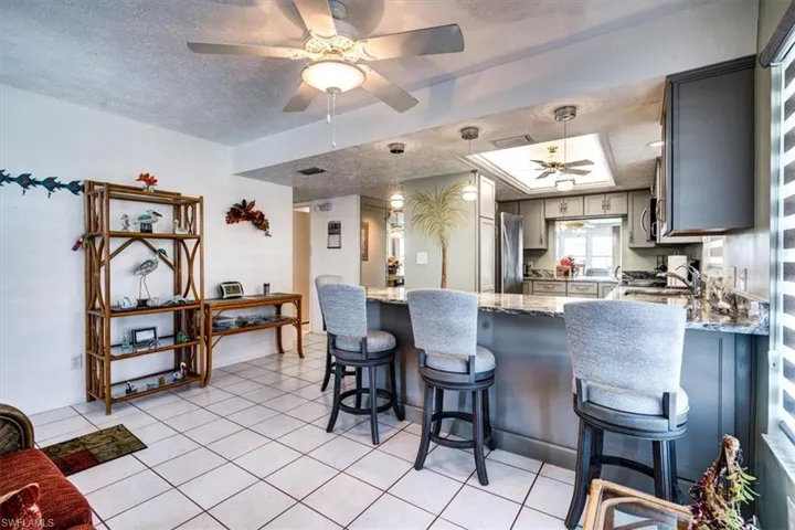 Kitchen featuring appliances with stainless steel finishes, a textured ceiling, gray cabinets, and light stone counters