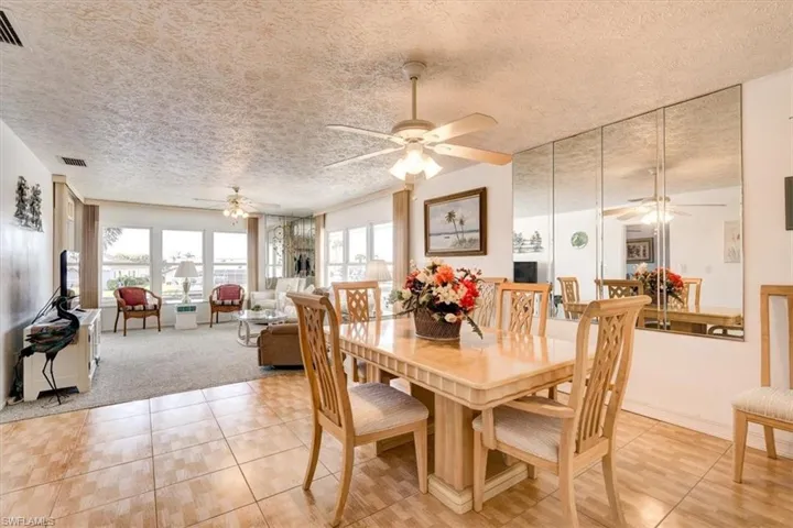 Dining area with ceiling fan, light tile patterned floors, and a textured ceiling