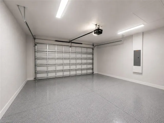 Spacious garage featuring a durable epoxy floor, a modern overhead garage door opener, and bright overhead strip lighting