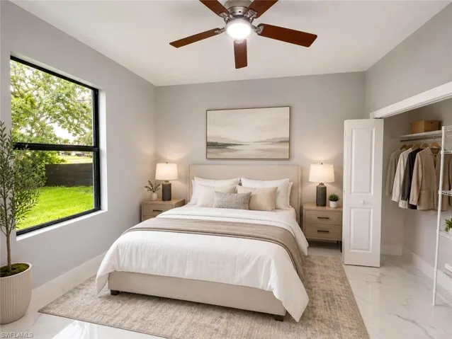 Well-lit interior space featuring expansive window, ceiling fan with integrated lighting, built-in closet with bifold door, and marble-look tile flooring