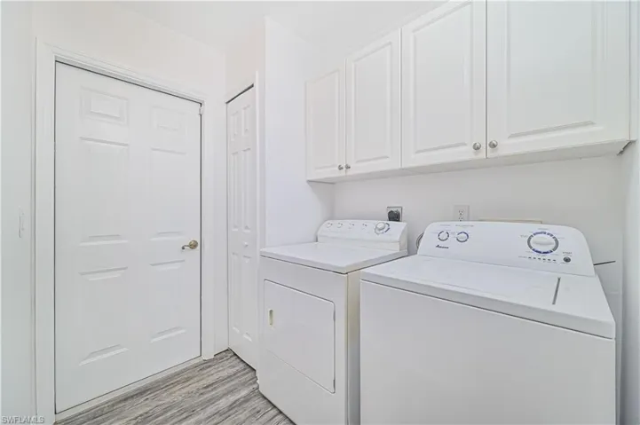 Laundry area with washer and clothes dryer, light hardwood / wood-style floors, and cabinets