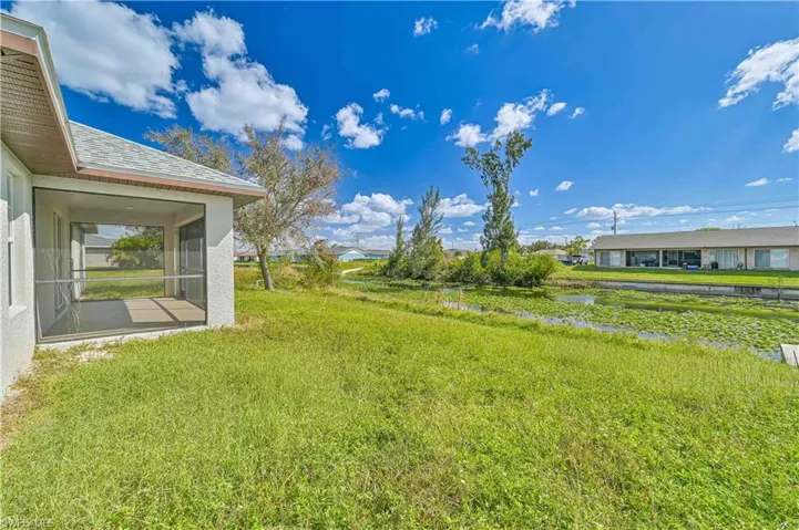 View of yard featuring a water view and a screened lanai