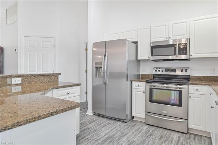 Kitchen featuring white cabinetry, stainless steel appliances, and granite counters