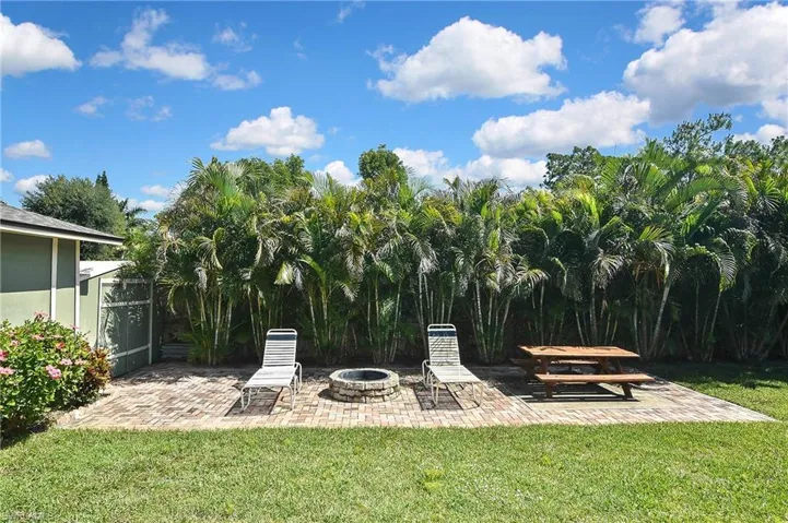 View of grassy yard featuring a patio and a fire pit
