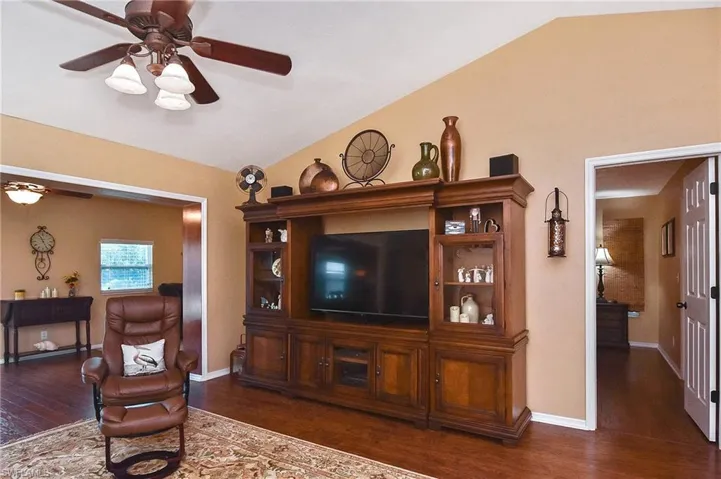 Living area with a ceiling fan, lofted ceiling, and wood finished floors