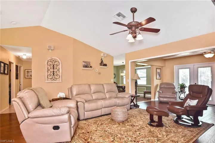 Living area featuring a ceiling fan, lofted ceiling, and wood finished floors
