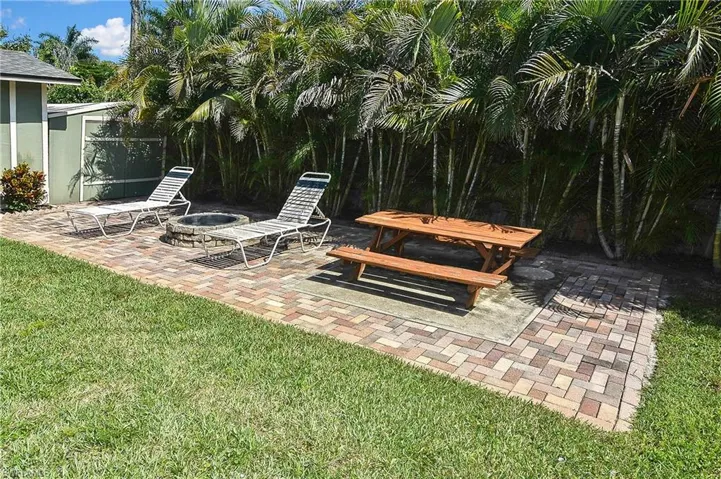 View of green lawn featuring an outdoor fire pit and a patio area