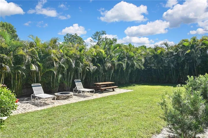 View of grassy yard with a patio and an outdoor fire pit
