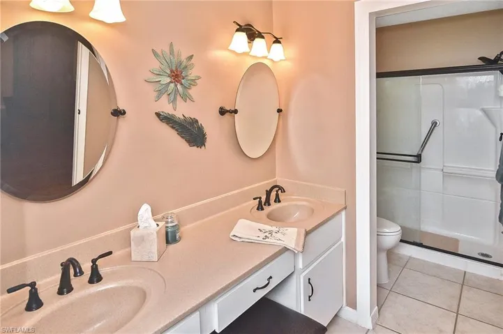 Full bath featuring double vanity, tile patterned flooring, and a shower