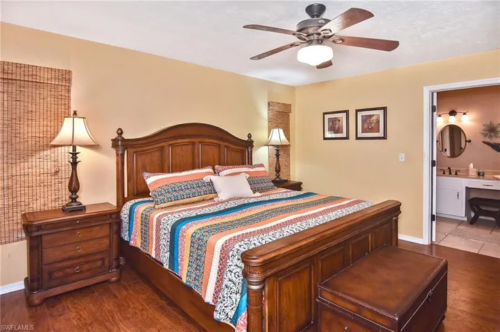 Bedroom featuring dark wood-style floors, ensuite bathroom, and a ceiling fan