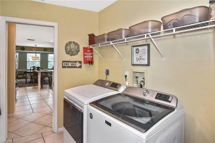 Laundry area with washer and dryer and light tile patterned floors