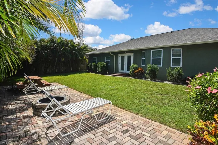 View of grassy yard featuring french doors, an outdoor fire pit, a patio area, and entry steps