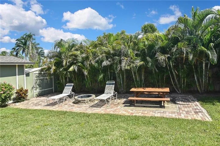 View of grassy yard with an outdoor fire pit and a patio