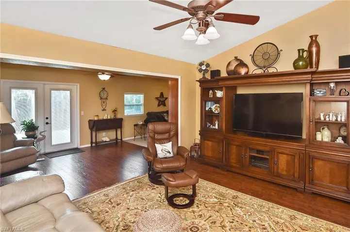 Living room with wood finished floors, a ceiling fan, french doors, and vaulted ceiling