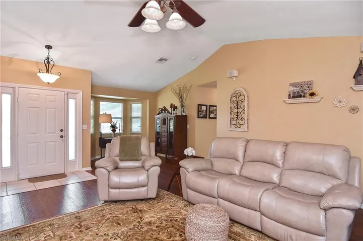 Living room featuring a ceiling fan, lofted ceiling, and wood finished floors