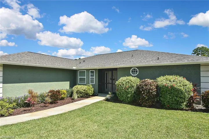 Single story home with stucco siding, a front yard, and a shingled roof