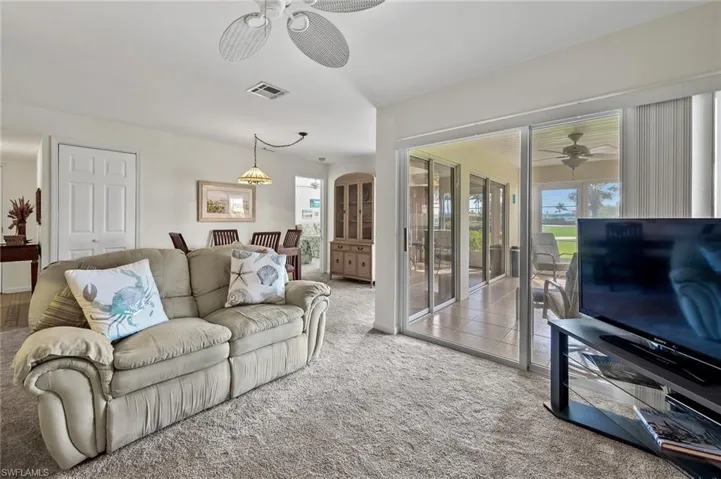 Living area featuring visible vents, a ceiling fan, and carpet