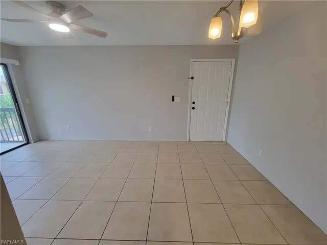 Spare room featuring light tile patterned floors, a chandelier, a textured ceiling, and a ceiling fan