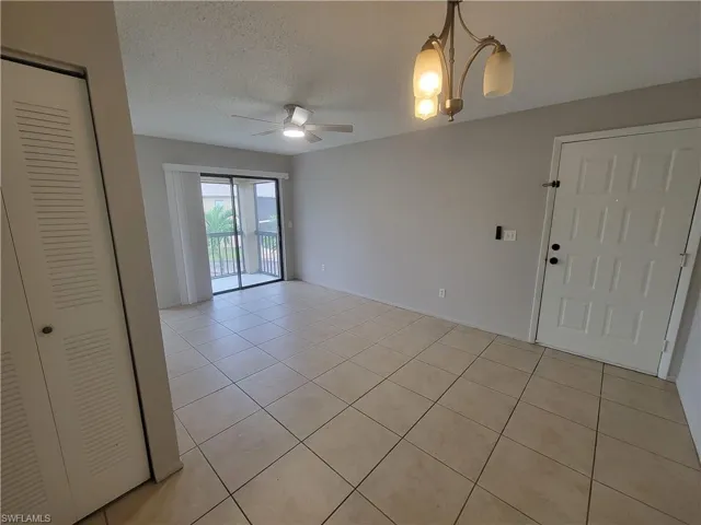 Unfurnished room with a textured ceiling, light tile patterned floors, a chandelier, and ceiling fan