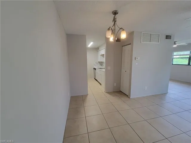 Unfurnished room featuring a chandelier, light tile patterned floors, a textured ceiling, and ceiling fan