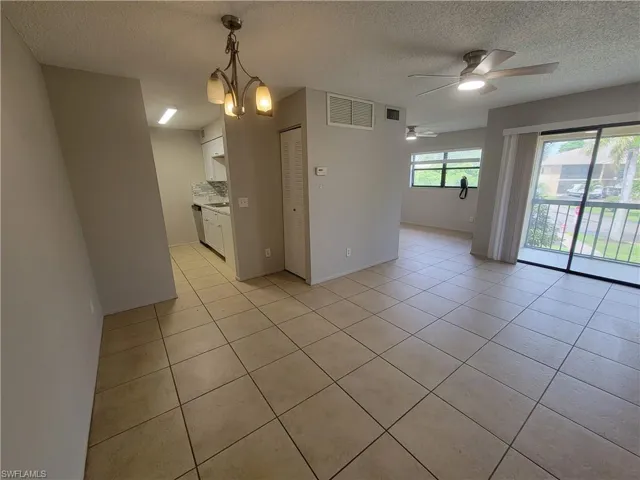 Kitchen with hanging light fixtures, white cabinets, light tile patterned floors, a chandelier, and light countertops