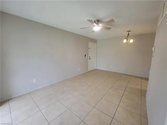 Spare room featuring light tile patterned floors, a chandelier, a textured ceiling, and a ceiling fan