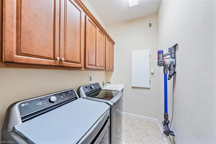 Separate laundry room with wood cabinets and a laundry tub.