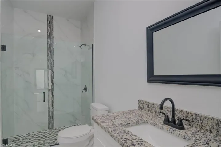 Bathroom featuring walk in shower, vanity, and toilet