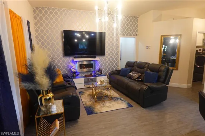 Living room with a notable chandelier, washer / dryer, and wood-type flooring