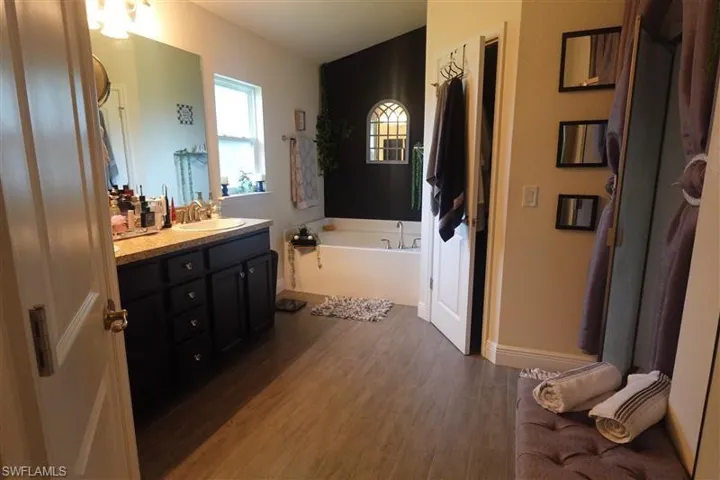 Bathroom with hardwood / wood-style flooring, a tub to relax in, and vanity