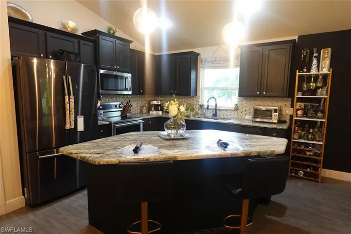 Kitchen featuring pendant lighting, sink, appliances with stainless steel finishes, and a kitchen island