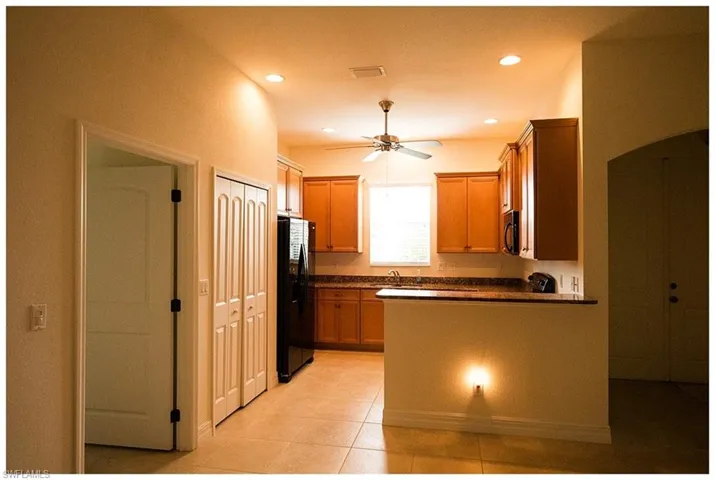 Kitchen with black appliances, light tile patterned floors, and ceiling fan