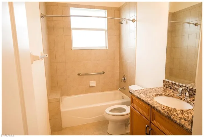Full bathroom with vanity, toilet, tiled shower / bath combo, and tile patterned floors