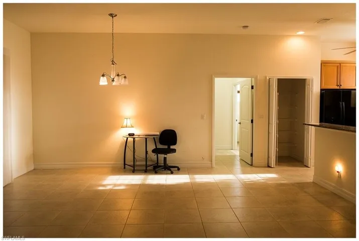Unfurnished room featuring ceiling fan with notable chandelier