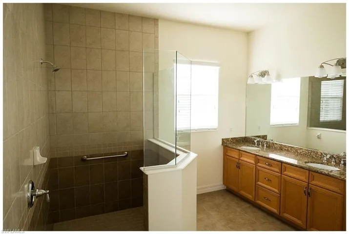 Bathroom with vanity, a tile shower, and tile patterned flooring